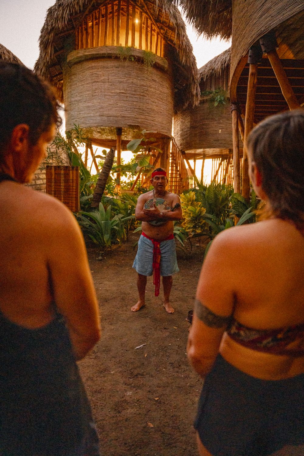 A local guide opening a temazcal ceremony at dusk, the group gathered around him